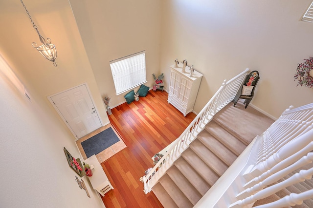 foyer featuring stairway, baseboards, wood finished floors, and a towering ceiling