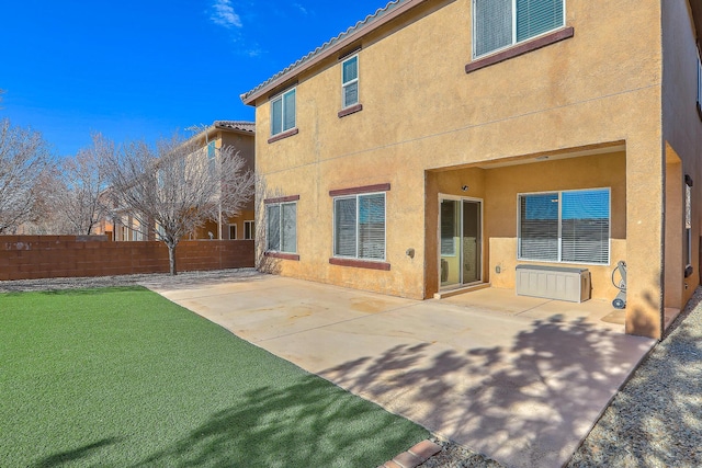 rear view of property with stucco siding, a tile roof, fence, a yard, and a patio area