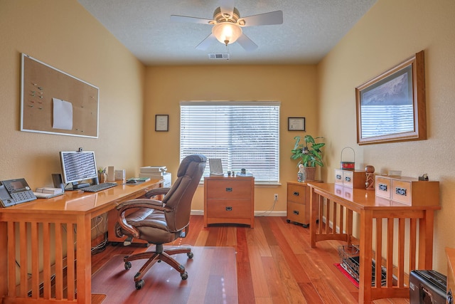 office area with visible vents, baseboards, ceiling fan, wood finished floors, and a textured ceiling