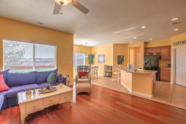 living area featuring visible vents, a textured ceiling, and light wood-type flooring