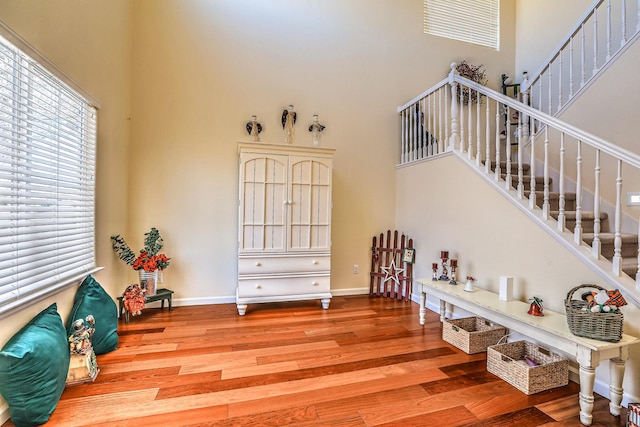 interior space featuring baseboards, a high ceiling, wood finished floors, and stairs