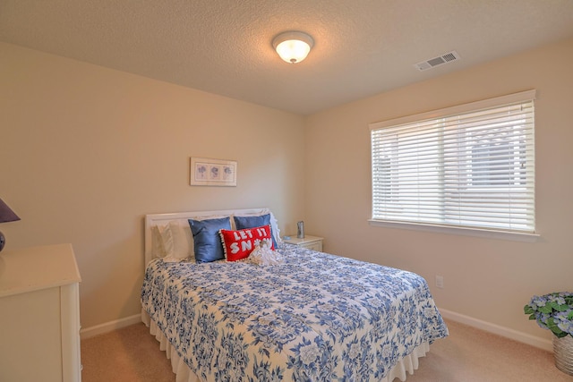 carpeted bedroom featuring visible vents, a textured ceiling, and baseboards