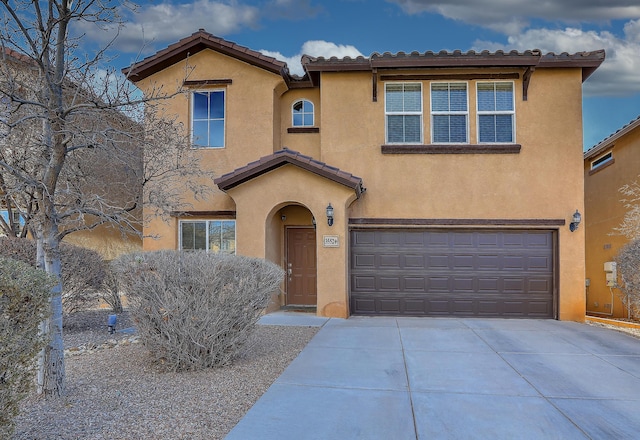 mediterranean / spanish-style home with a tile roof, concrete driveway, a garage, and stucco siding