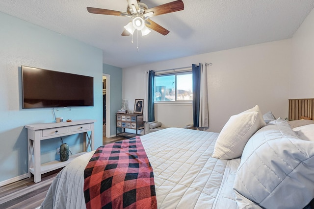 bedroom with ceiling fan, a textured ceiling, and wood-type flooring