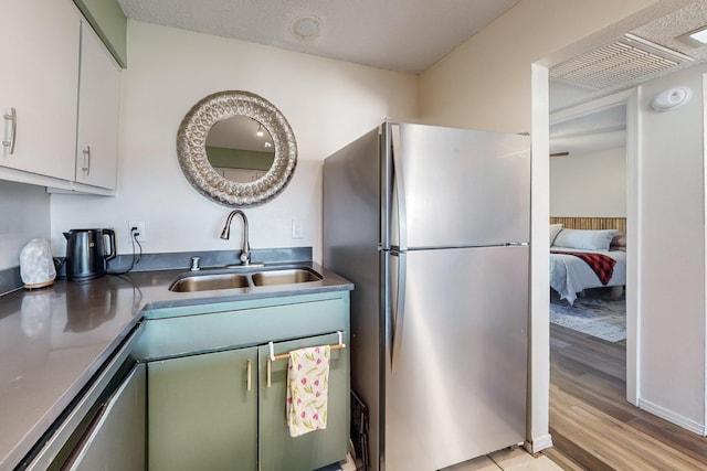 kitchen with light hardwood / wood-style floors, sink, white cabinets, and stainless steel fridge