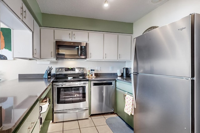 kitchen with light tile patterned flooring, stainless steel appliances, a textured ceiling, and white cabinets