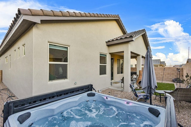 rear view of house with a patio area and a hot tub