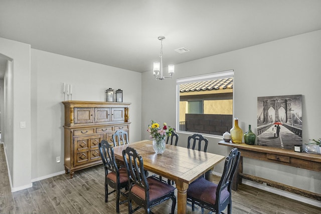 dining space with wood-type flooring and a notable chandelier