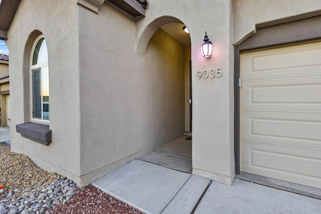 property entrance with stucco siding and an attached garage