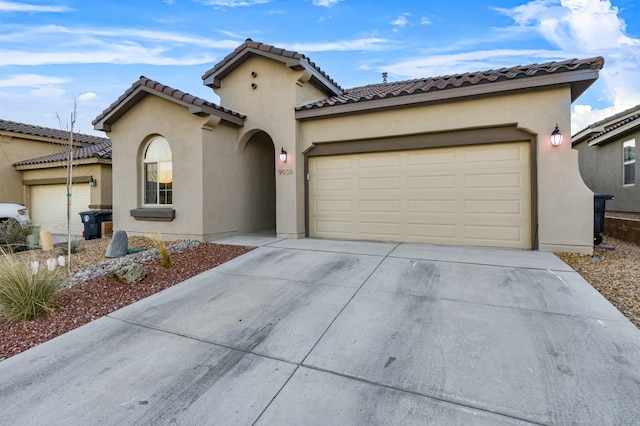 mediterranean / spanish-style home with stucco siding, driveway, an attached garage, and a tiled roof