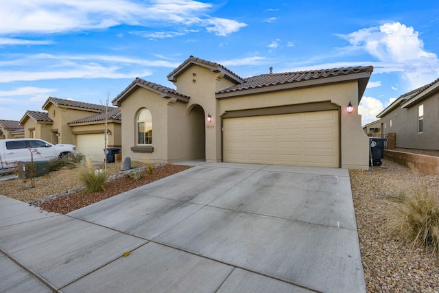 mediterranean / spanish-style house featuring a tiled roof, stucco siding, an attached garage, and concrete driveway