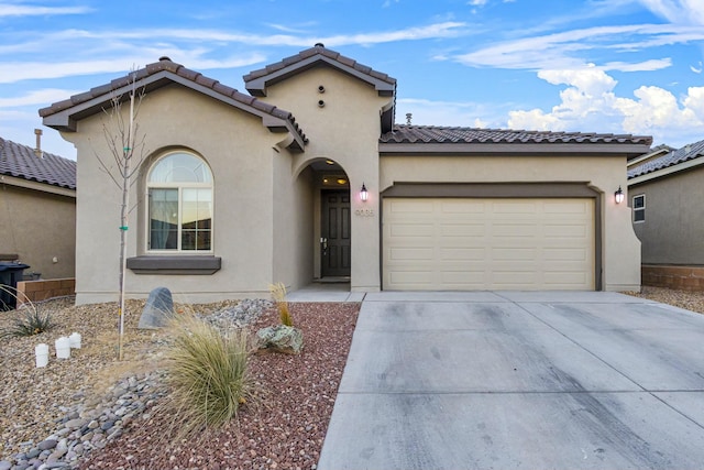 mediterranean / spanish home featuring stucco siding, a garage, driveway, and a tile roof