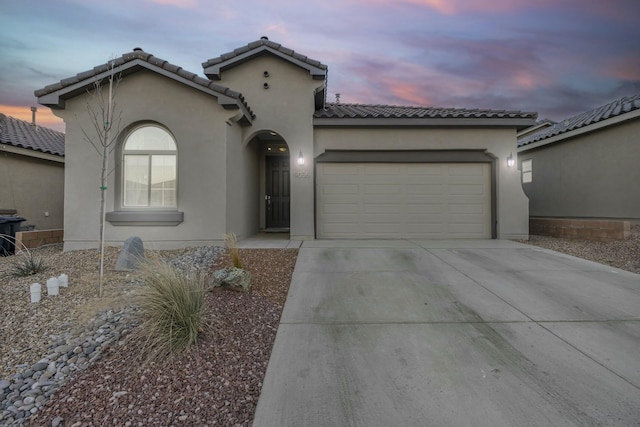 mediterranean / spanish-style house with stucco siding, driveway, an attached garage, and a tile roof