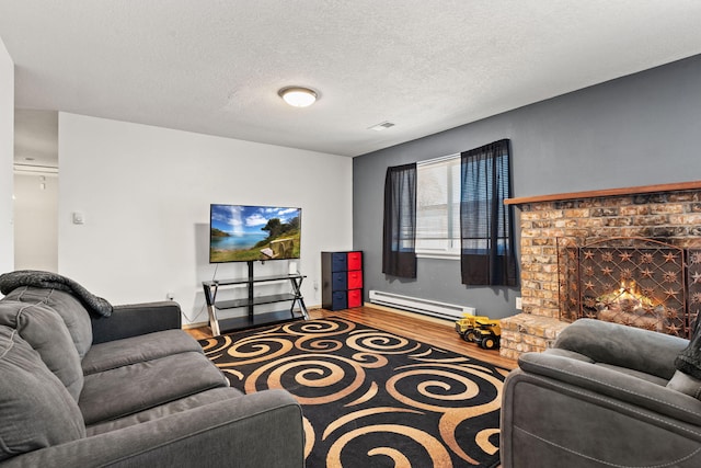 living room featuring a brick fireplace, hardwood / wood-style floors, a baseboard heating unit, and a textured ceiling