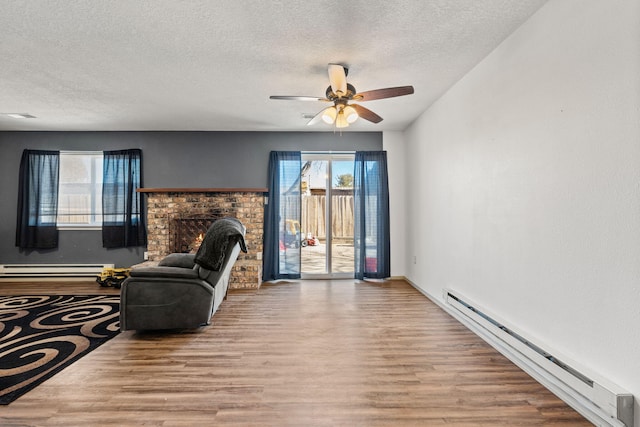 living room with a baseboard heating unit, a brick fireplace, and light hardwood / wood-style floors