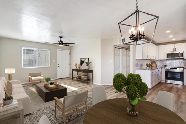 living room with wood-type flooring and ceiling fan with notable chandelier