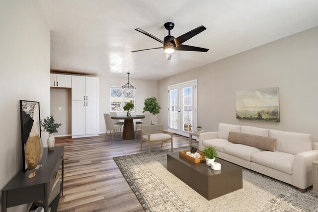 living room featuring light wood-type flooring, ceiling fan, and french doors