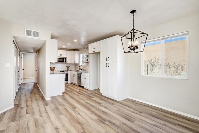 kitchen with decorative light fixtures, light hardwood / wood-style floors, sink, stainless steel appliances, and white cabinets