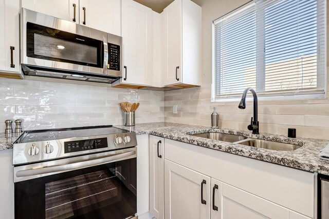 kitchen with stainless steel appliances, white cabinetry, and sink