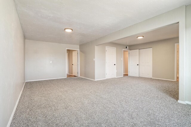 unfurnished room with a textured ceiling and carpet flooring