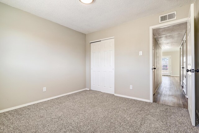 unfurnished bedroom with a textured ceiling, a closet, and carpet flooring