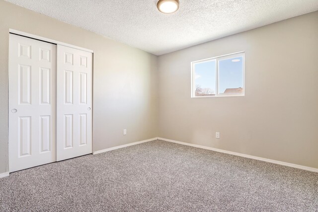 unfurnished bedroom with a textured ceiling, a closet, and carpet floors