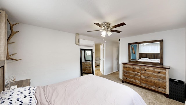 bedroom featuring an AC wall unit, light colored carpet, connected bathroom, and ceiling fan