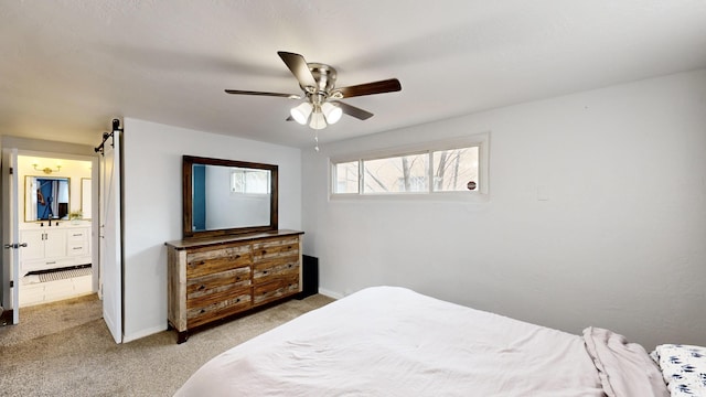 bedroom featuring ceiling fan, ensuite bathroom, a barn door, and light colored carpet