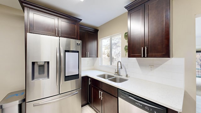 kitchen featuring backsplash, appliances with stainless steel finishes, sink, and light stone counters