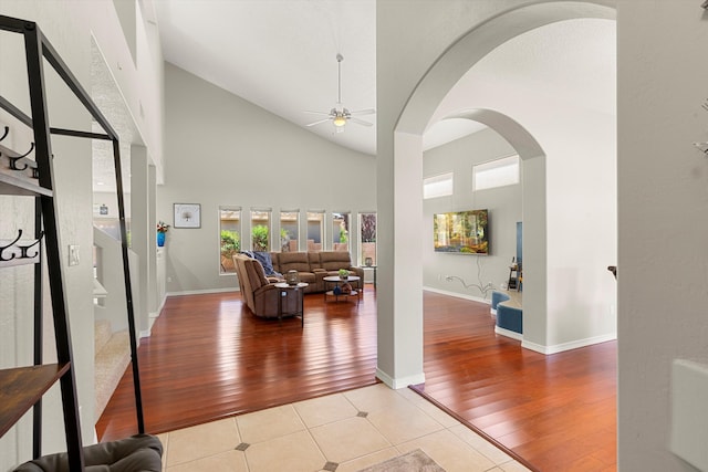 foyer with ceiling fan, high vaulted ceiling, and light hardwood / wood-style floors