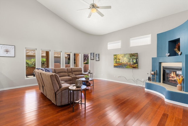 living room featuring dark hardwood / wood-style flooring, high vaulted ceiling, and ceiling fan