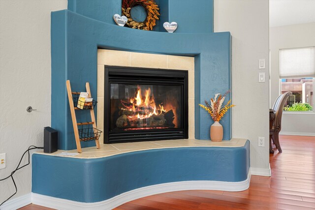 details with hardwood / wood-style flooring and a tiled fireplace