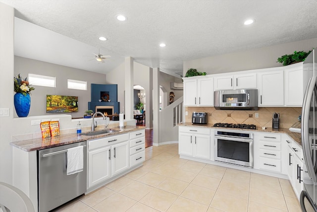 kitchen featuring stainless steel appliances, kitchen peninsula, sink, and white cabinets