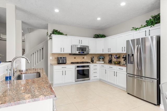 kitchen with tasteful backsplash, stainless steel appliances, sink, and white cabinets