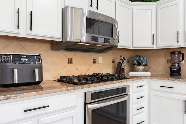 kitchen with tasteful backsplash, appliances with stainless steel finishes, and white cabinets