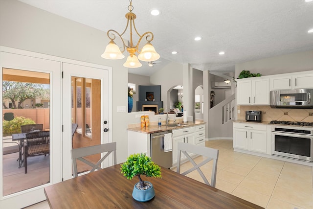 tiled dining space featuring vaulted ceiling, sink, a notable chandelier, and a textured ceiling