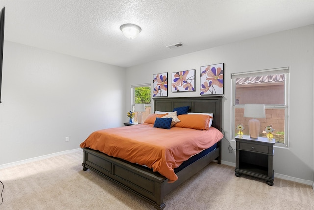 bedroom featuring light colored carpet and a textured ceiling