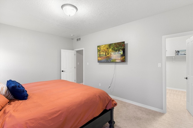 carpeted bedroom featuring a spacious closet and a textured ceiling