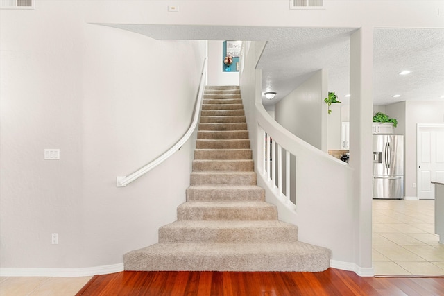 staircase with wood-type flooring and a textured ceiling