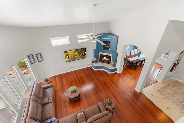 living room with ceiling fan, vaulted ceiling, hardwood / wood-style floors, and a textured ceiling