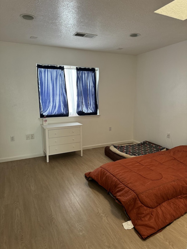 bedroom with a textured ceiling and wood-type flooring