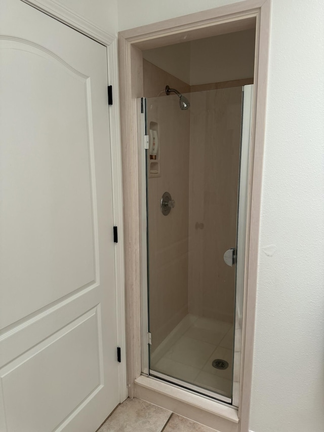 bathroom with a shower with shower door and tile patterned floors