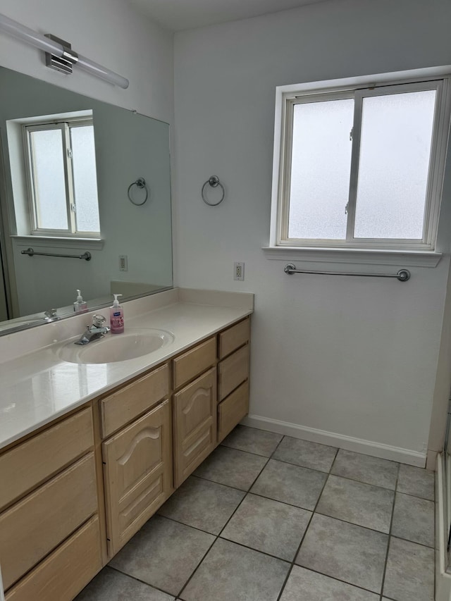 bathroom with tile patterned flooring, vanity, and a healthy amount of sunlight