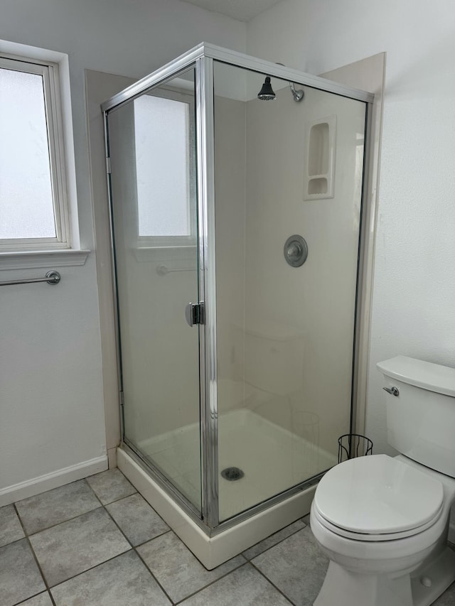 bathroom featuring toilet, an enclosed shower, and tile patterned floors