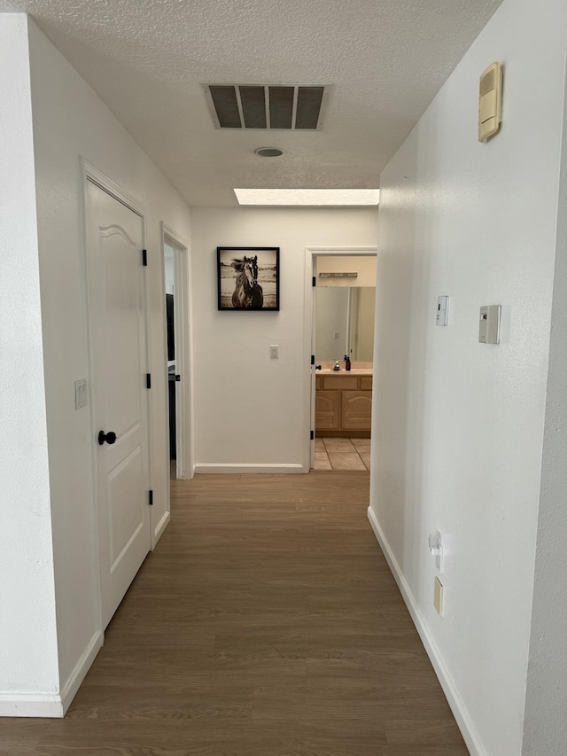 corridor featuring hardwood / wood-style floors, a skylight, and a textured ceiling