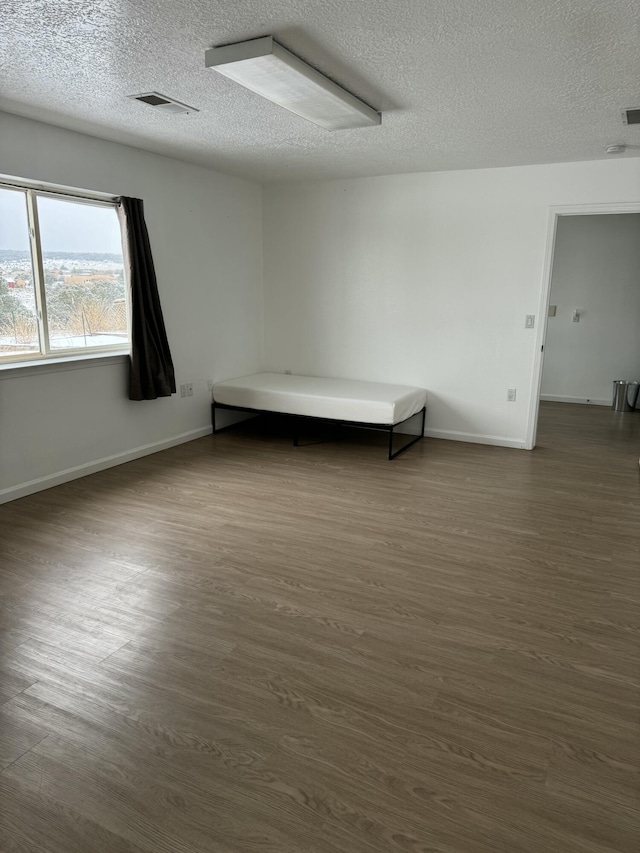 interior space with a textured ceiling and dark hardwood / wood-style flooring