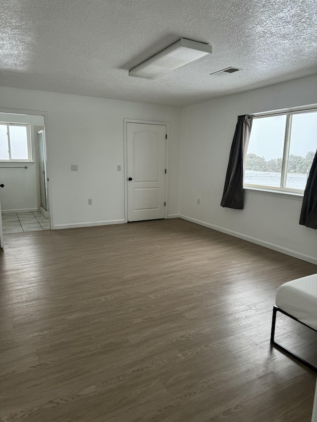 empty room with wood-type flooring, a wealth of natural light, and a textured ceiling