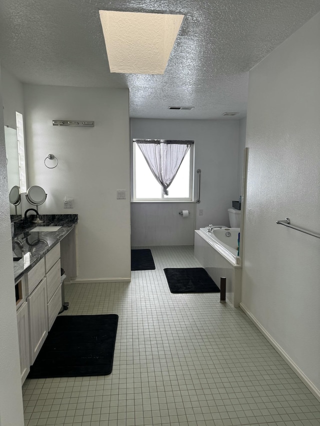 bathroom featuring a textured ceiling, tile patterned floors, vanity, and a tub to relax in