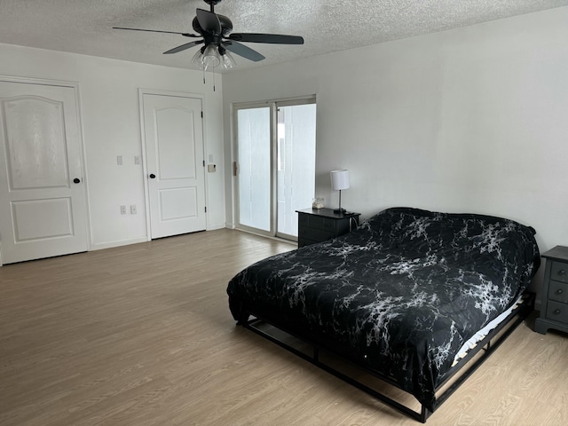 bedroom with ceiling fan, a textured ceiling, and light wood-type flooring