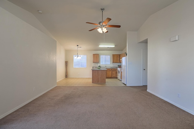 unfurnished living room featuring ceiling fan with notable chandelier, light colored carpet, and lofted ceiling